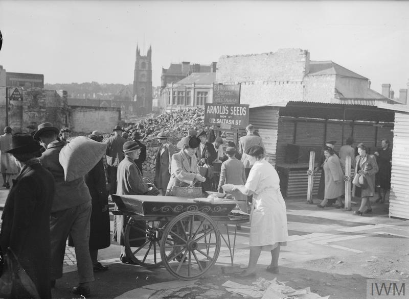 Civilians shop from temporary stalls among the remains of bomb-damaged buildings in Plymouth.